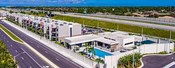A road with a white building and a pool on the side.