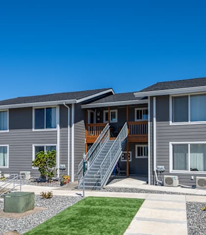 A row of houses with grey siding and white trim.