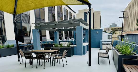 A patio with a table and chairs under a yellow canopy.