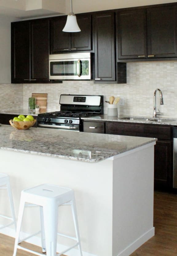 a kitchen with black cabinets and a white island with a laptop on it
