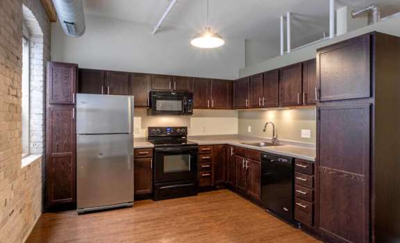 A kitchen with dark wood cabinets and a white refrigerator.