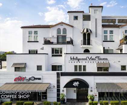 A white building with a black awning and a sign that says "Hollywood View Towers Luxury Apartments".