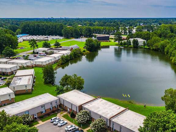 A serene landscape with a lake, greenery, and a building complex.