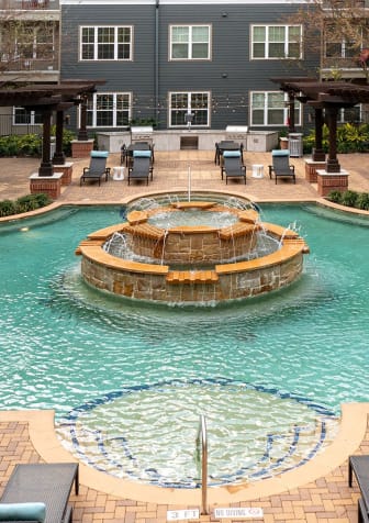 a swimming pool with a fountain in front of an apartment building