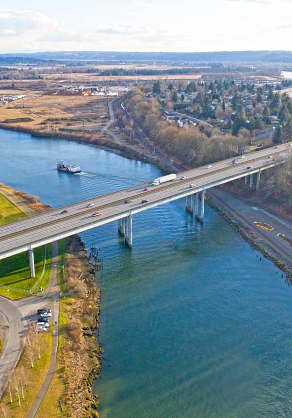 A bridge spans a river with a town in the background.
