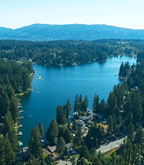 A serene lake surrounded by lush greenery and nestled between mountains.