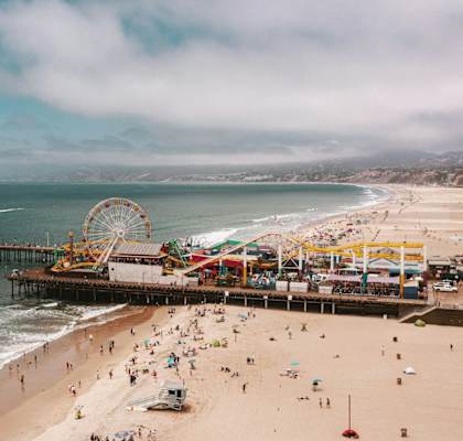 a crowded beach with a pier and a ferris wheel