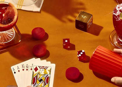 a hand playing a game of cards and dice on a table at The Fitzgerald in Spartanburg, SC 29302