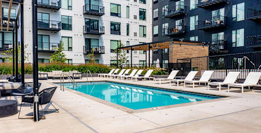an outdoor pool with lounge chairs and a building in the background
