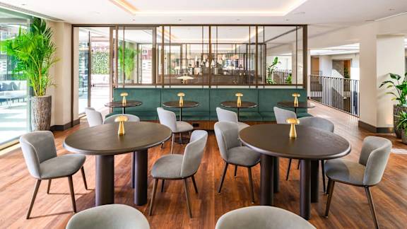 A modern dining room with a glass partition and a wooden table.