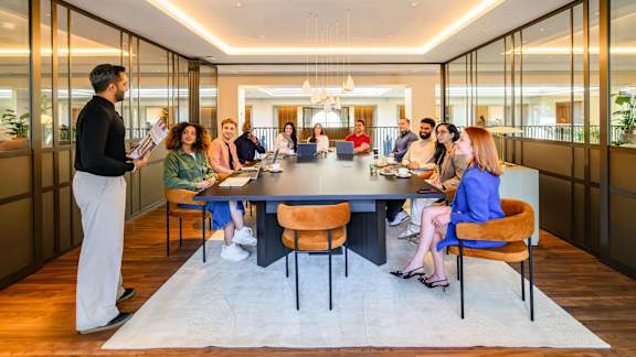 A group of people are sitting around a table in a meeting room.