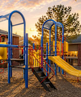 A playground with a yellow slide and a blue structure.