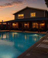 A swimming pool in front of a house at sunset.