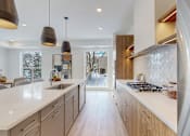 Thumbnail 29 of 51 - A modern kitchen with a long white counter and wooden cabinets.