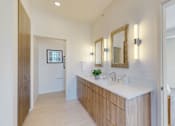 Thumbnail 40 of 51 - A bathroom with a vanity, mirror, and a plant.