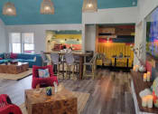 Thumbnail 55 of 60 - Fusion Orlando apartments lounge with colorful midcentury modern seating and decor, coffee center, and bar height table with wicker back chairs.