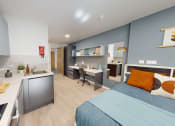 Thumbnail 6 of 8 - a bedroom with a bed and a desk in a small room