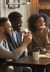 group of people eating pizza at a restaurant