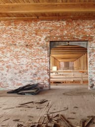 Interior of Converse Mill Lofts before conversion, with bare brick walls, open doorway, and renovation debris.