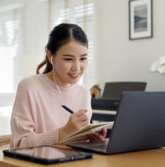 Woman Smiling while Wearing Headphones and Working on Laptop