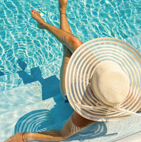 A woman in a straw hat is floating in a pool.