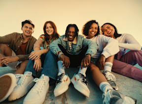 Five people are sitting together wearing sneakers.