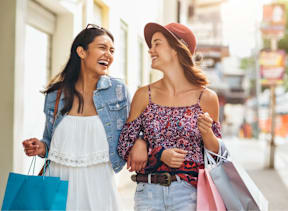 Two women walking on the street with shopping bags.