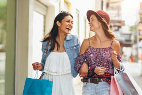 two women walking down the street with shopping bags