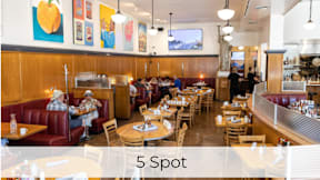 A restaurant with wooden booths and tables with people sitting and standing.at Axle, Seattle, WA 98119