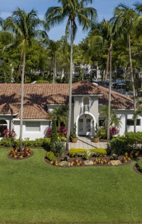 a mansion with a green lawn and palm trees