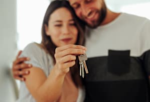 A man and woman are holding keys together.
