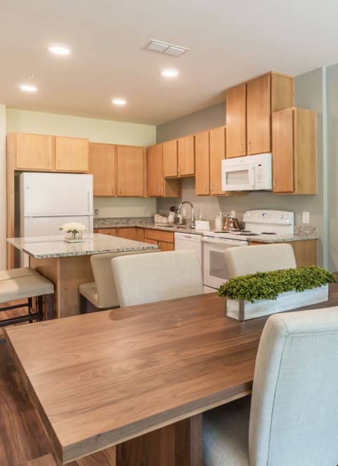 a living room with a white couch and two white chairs with blue and white pillows at Juniper Square 55+ Apartments, Glendale Arizona