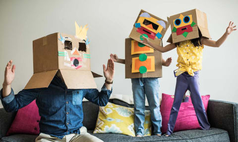 three people sitting on a couch wearing cardboard boxes on their heads