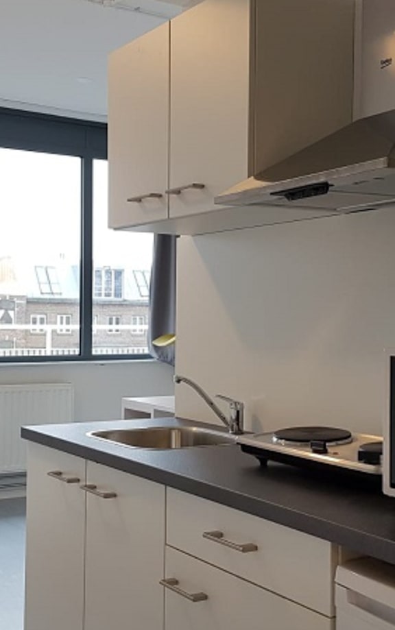 A kitchen with a white counter and a window overlooking a cityscape.