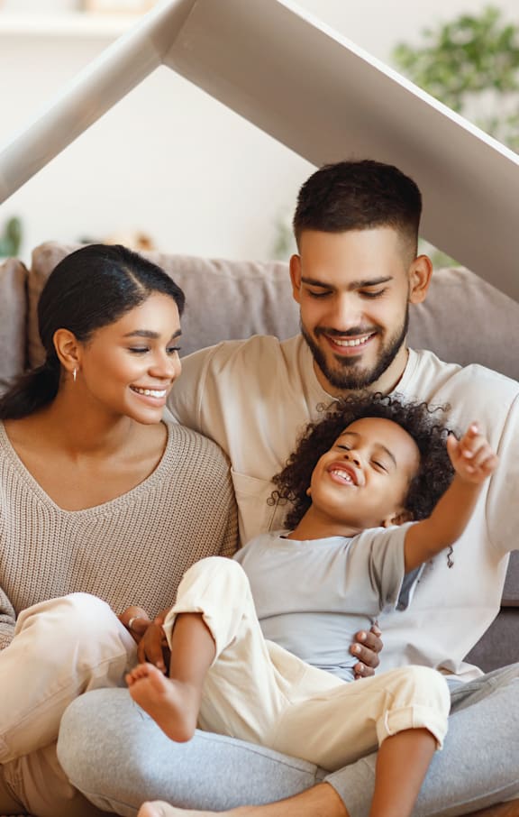 a young family sitting on the floor in their living room under a roof