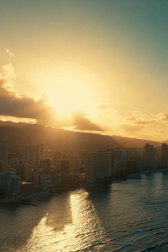 A cityscape with buildings and a body of water under a sunset.