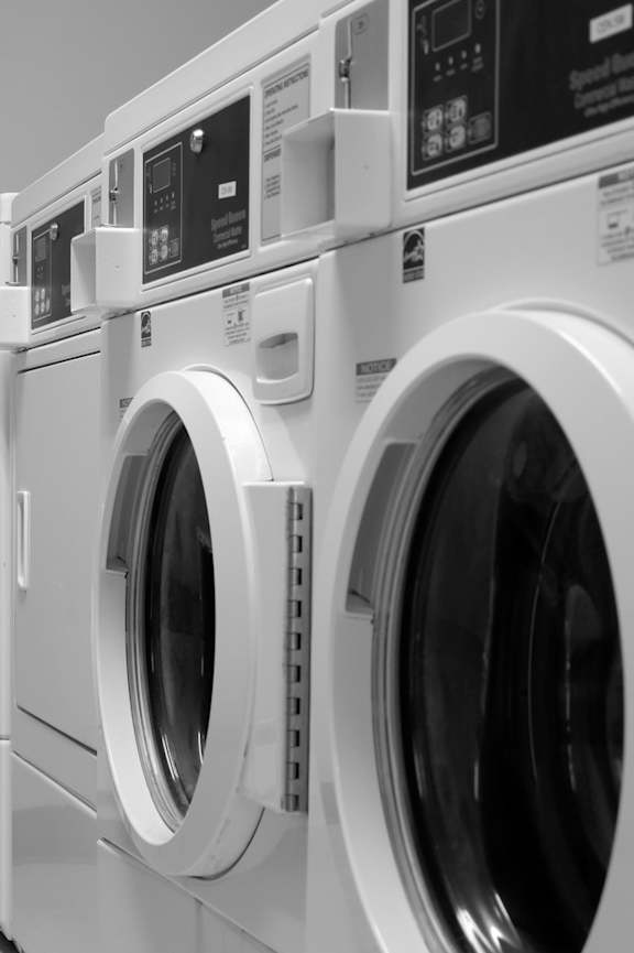 A row of white front load washing machines in a laundromat.