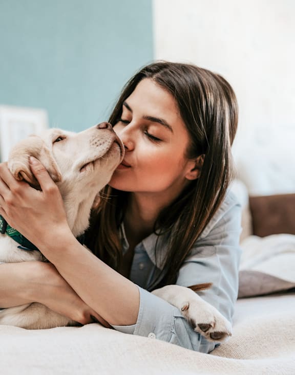 A woman is lying on a bed with her dog.