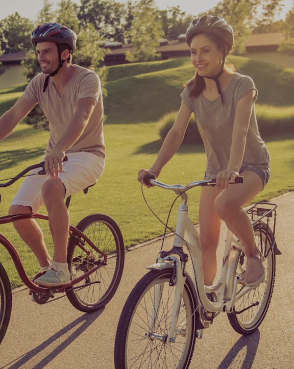 A man and a woman are riding bicycles on a path.