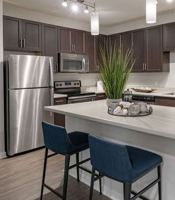 A kitchen with a white island and blue chairs.