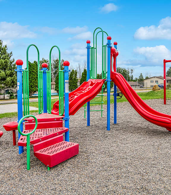 a playground with a red slide and monkey bars in a park