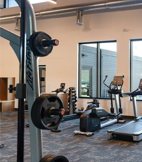 Gym with cardio machines and weights on the floor at The Bosk Apartment Homes, Woodbury, 55125