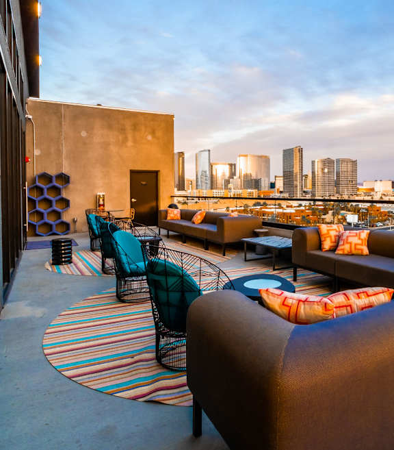 A rooftop patio with a view of the city skyline at dusk.