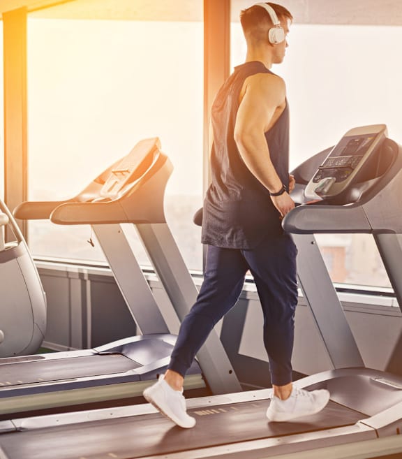 A man is running on a treadmill in a gym.