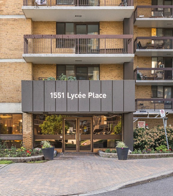 The image shows a multi-story residential building with a sign that reads "1551 Lycée Place".