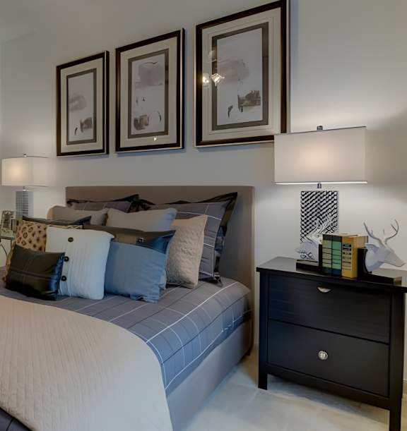 A bedroom with a bed, nightstand, and three framed pictures on the wall.