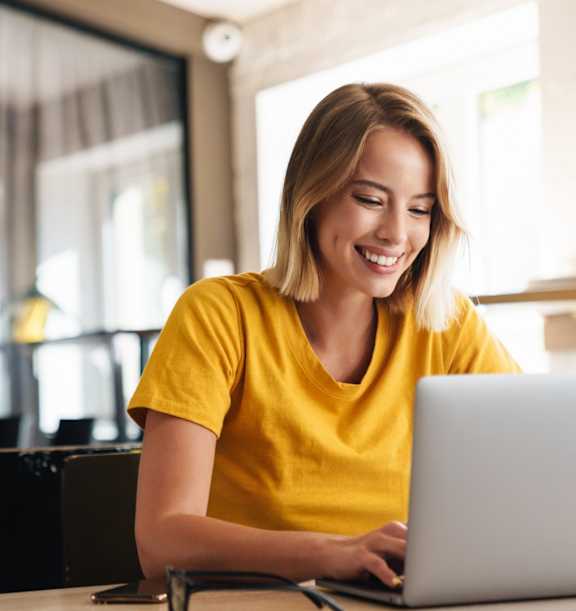 A woman in a yellow shirt is using a laptop at The Maverick Apartments, Kitchener, Ontario