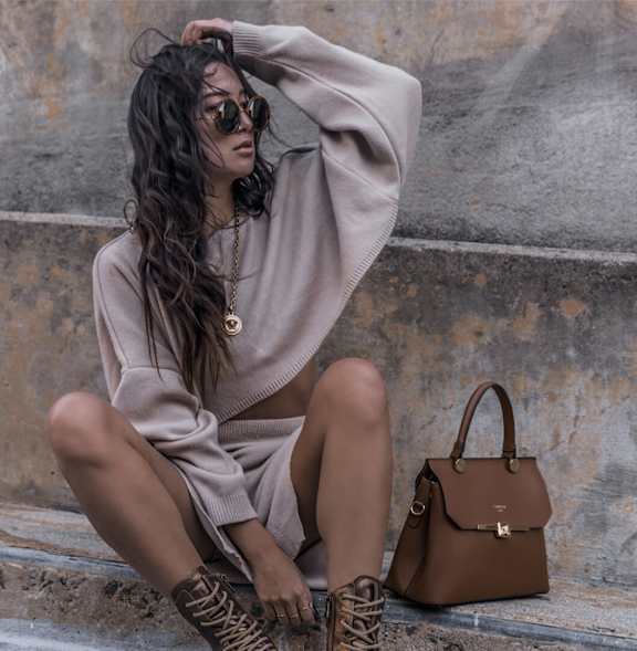 a woman sitting on the steps with her hand in her hair and holding a bag