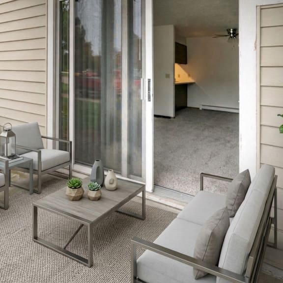 A patio with a table, chairs, and potted plants.
