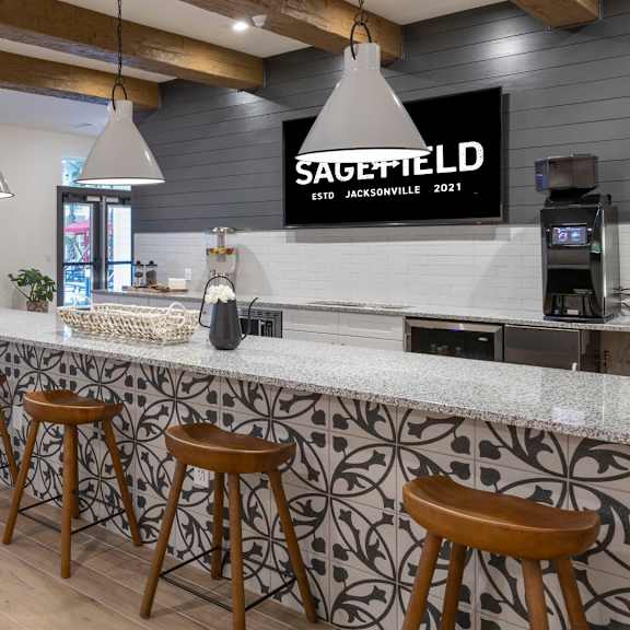 A modern bar with wooden stools and a counter.